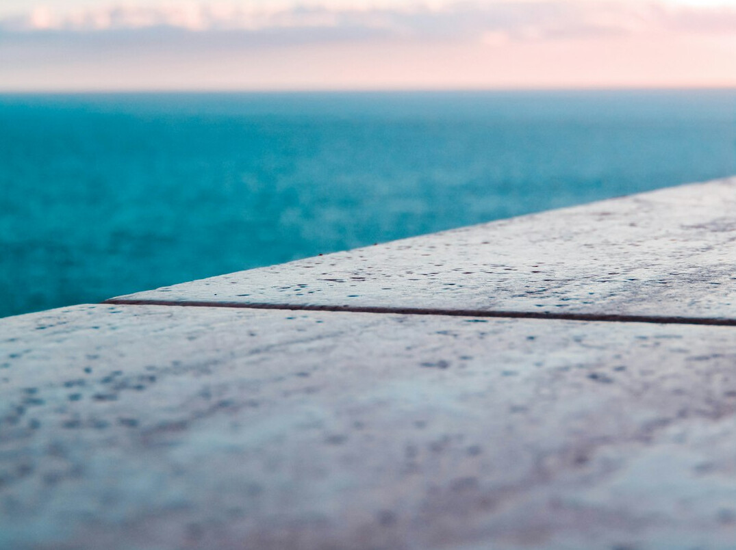 Close-up of travertine pool deck and ocean horizon at sunset